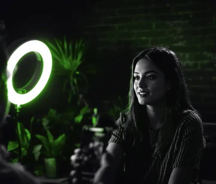 Mujer frente a un aro de luz mientras la graban con un celular para redes, el día a día de una agencia de redes sociales