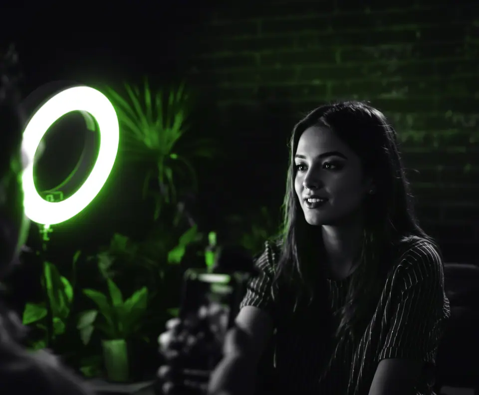 Mujer frente a un aro de luz mientras la graban con un celular para redes, el día a día de una agencia de redes sociales