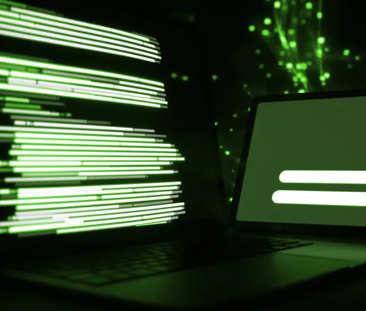 Laptop with glowing green lines of code next to a tablet showing a simple interface, a snapshot of AI MVP development at work