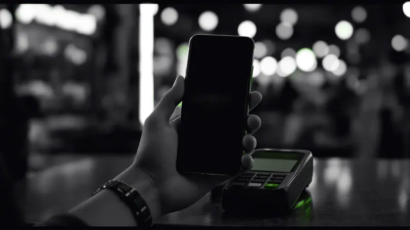 Fintech en Colombia: pago digital desde un celular en una tienda de barrio, con la señal de la transacción resaltada en verde