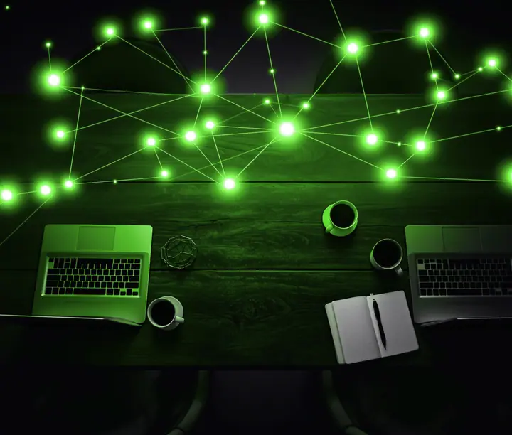 Overhead view of a table with two laptops and coffee under a network of glowing green nodes: DataLab LinkedIn prospecting case study