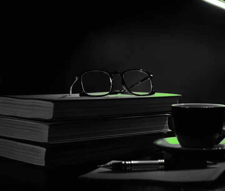 Stacked books, reading glasses and a coffee cup under a green desk lamp, cover of DataLab's digital marketing blog