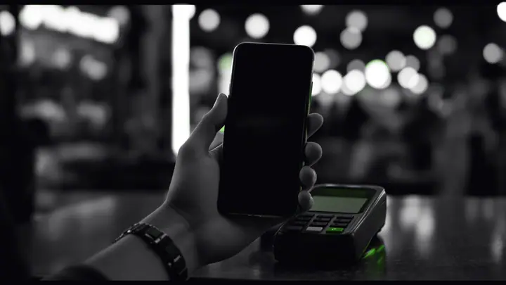 Fintech in Colombia: a digital payment from a smartphone at a neighborhood store, with the transaction signal highlighted in green