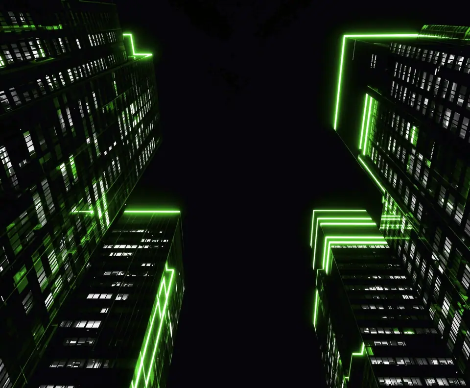 Torres de oficinas vistas desde abajo, de noche, con líneas de luz verde en sus bordes: caso de la web corporativa en WordPress de la fintech IRIS