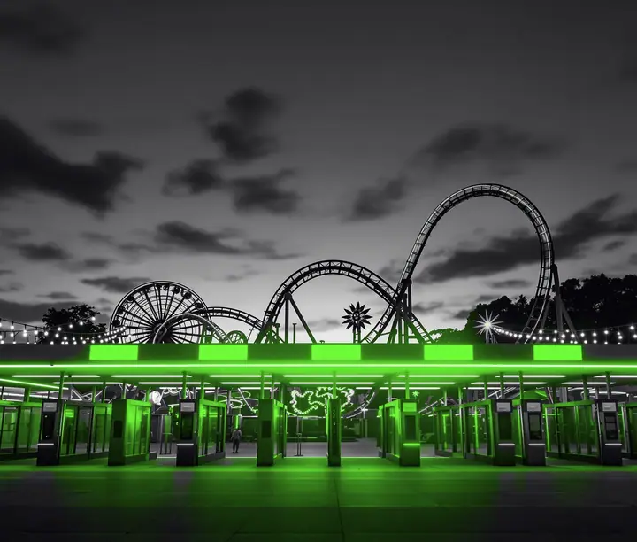 Amusement park entrance at dusk with lit turnstiles and a roller coaster behind: Mundo Aventura QR ticketing e-commerce case study