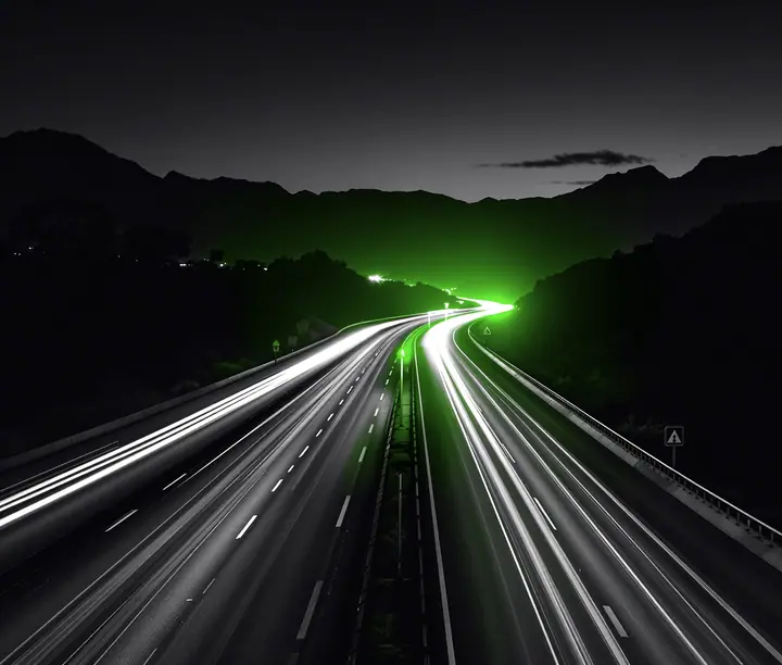 Avenida de varios carriles al anochecer, con estelas de luz de carros y motos y montañas al fondo: caso de venta de SOAT digital de Seguros Mundial