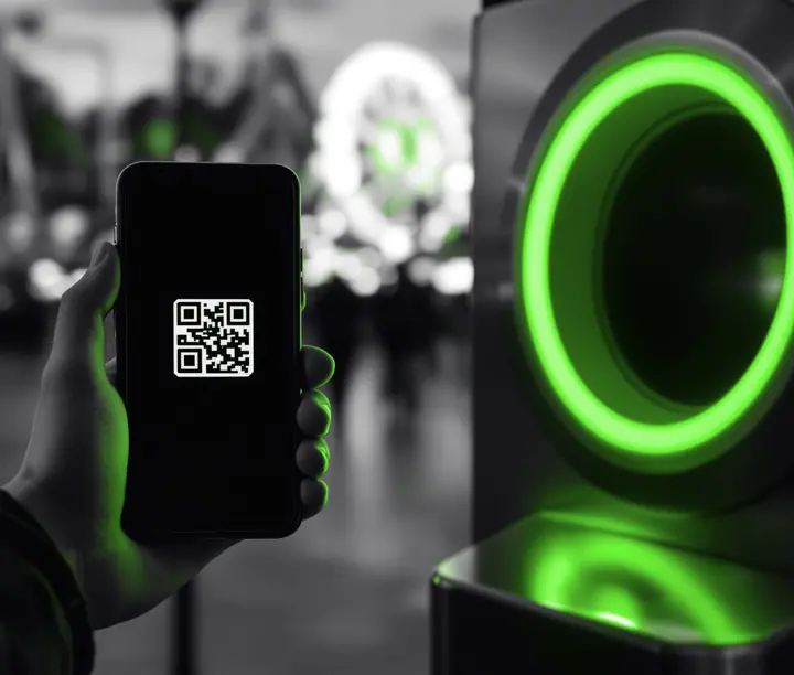Phone with a QR e-ticket held up to an amusement park entry scanner, the kind of online-to-gate sale a Shopify development agency builds